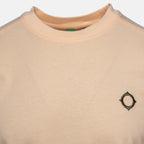 Close-up of a crewneck sweatshirt in a light peach-beige color, featuring a small dark green geometric logo on the left chest. MA.Strum T-Shirt available at Sakks Menswear in Southampton.