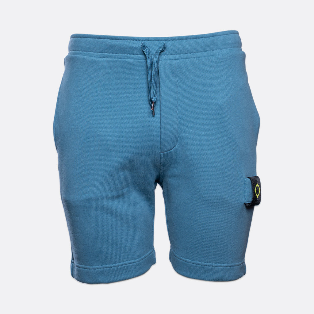 Blue sweat shorts with a drawstring waist and a signature pocket flap on the left leg, shown against a light gray background. MA.Strum Sweat Shorts available at Sakks Menswear in Southampton.