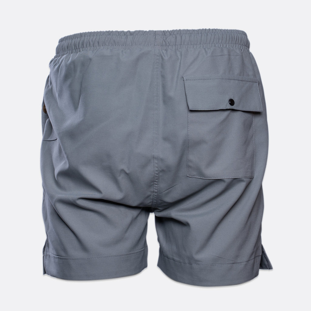 Gray athletic shorts shown from the back, featuring an elastic waistband, a side pocket with a button flap, and a side slit on the right leg, set against a plain light gray background. MA.Strum Swimwear available at Sakks Menswear in Southampton.