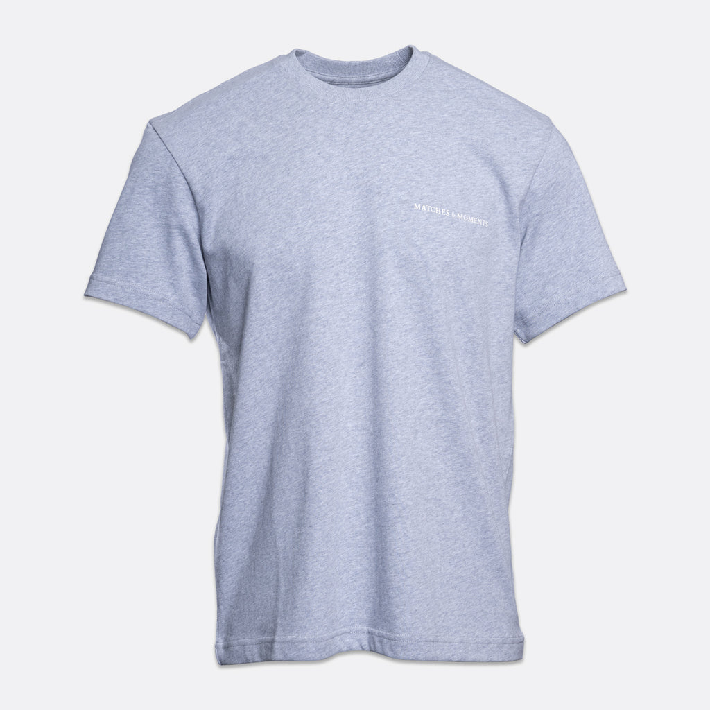 A light heather gray short-sleeve crewneck t-shirt with a small white 'MATCHES & MOMENTS' logo printed on the left chest, displayed against a light gray background. PAIGE T-Shirt available at Sakks Menswear in Southampton.