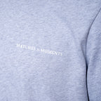 Close-up of a heather gray sweatshirt with the words 'MATCHES & MOMENTS' printed in white across the chest. PAIGE T-Shirt available at Sakks Menswear in Southampton.