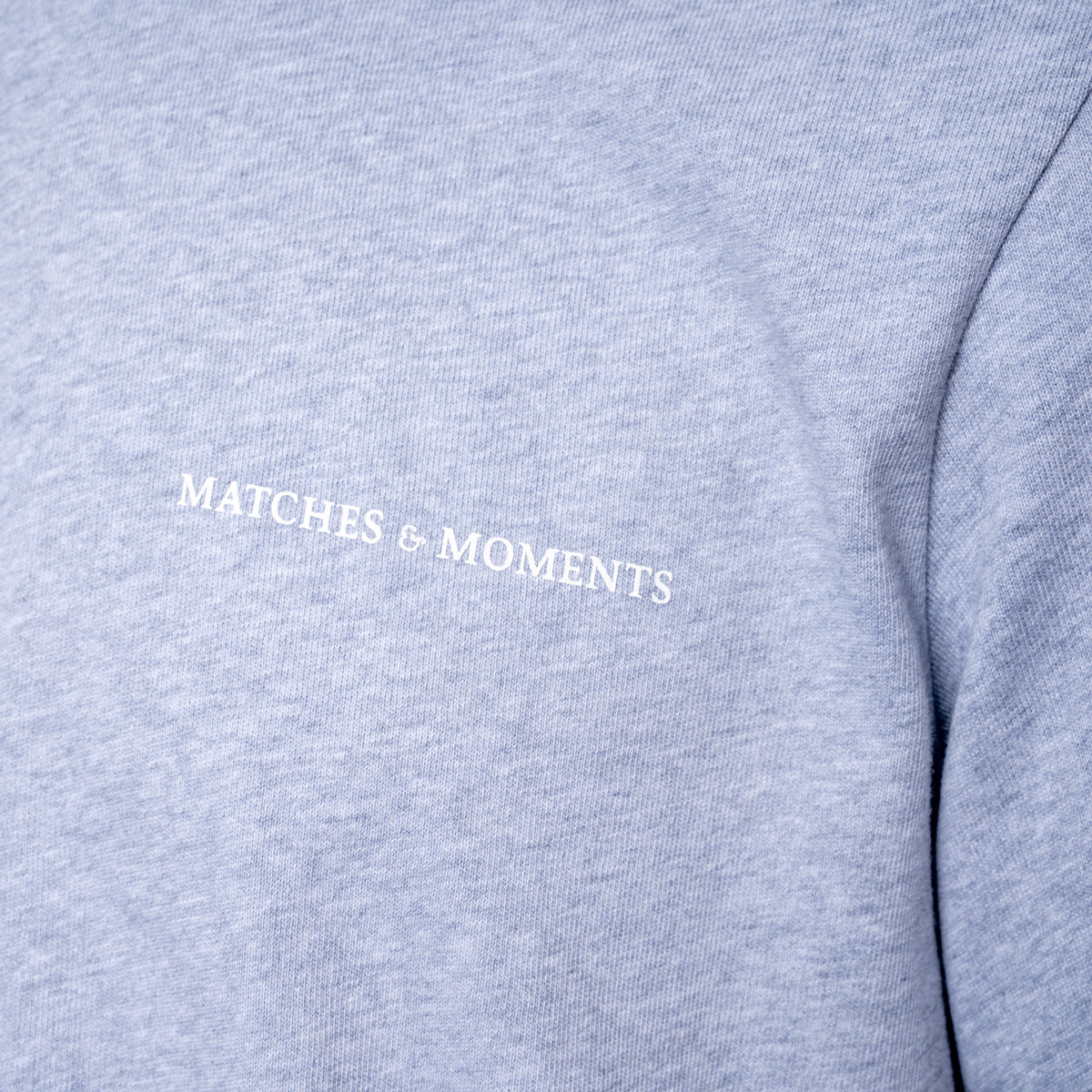Close-up of a heather gray sweatshirt with the words 'MATCHES & MOMENTS' printed in white across the chest. PAIGE T-Shirt available at Sakks Menswear in Southampton.