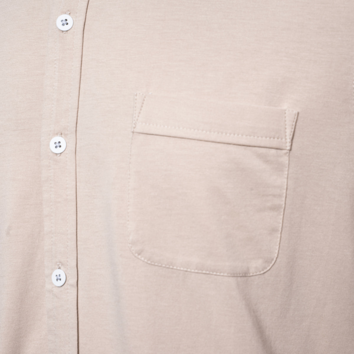 Close-up of a light beige or cream-colored short-sleeve button-up shirt with a chest pocket and white  PAIGE Shirt available at Sakks Menswear in Southampton.buttons.