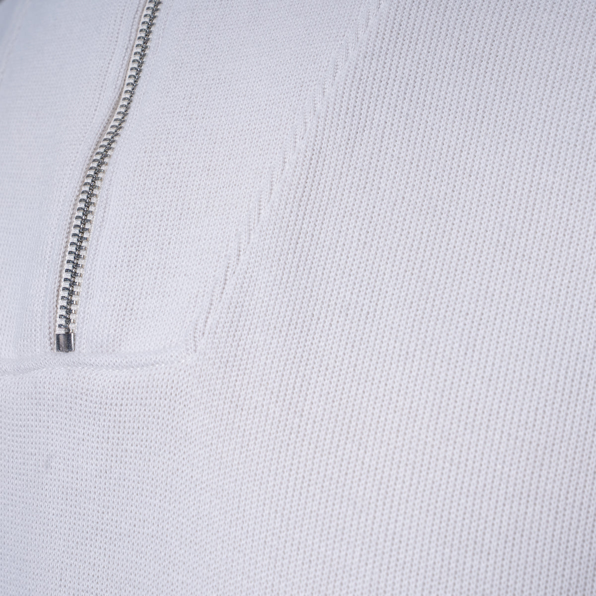Close-up of a white textured knit garment with a silver metal zipper running vertically. PAIGE Sweatshirt available at Sakks Menswear in Southampton.