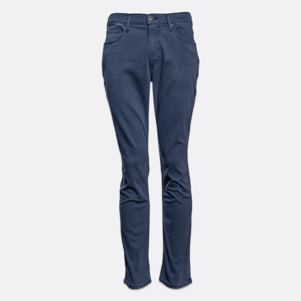 A pair of slim-fit blue jeans shown flat against a light gray background. PAIGE Jeans available at Sakks Menswear in Southampton.