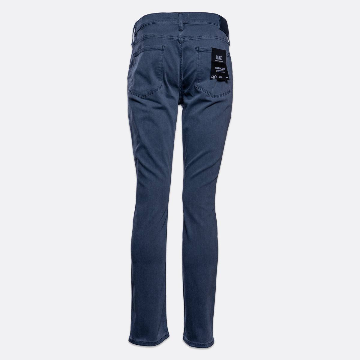 A pair of slim-fit blue jeans shown from the back, featuring a black brand patch on the right back pocket, set against a plain light gray background. PAIGE Jeans available at Sakks Menswear in Southampton.