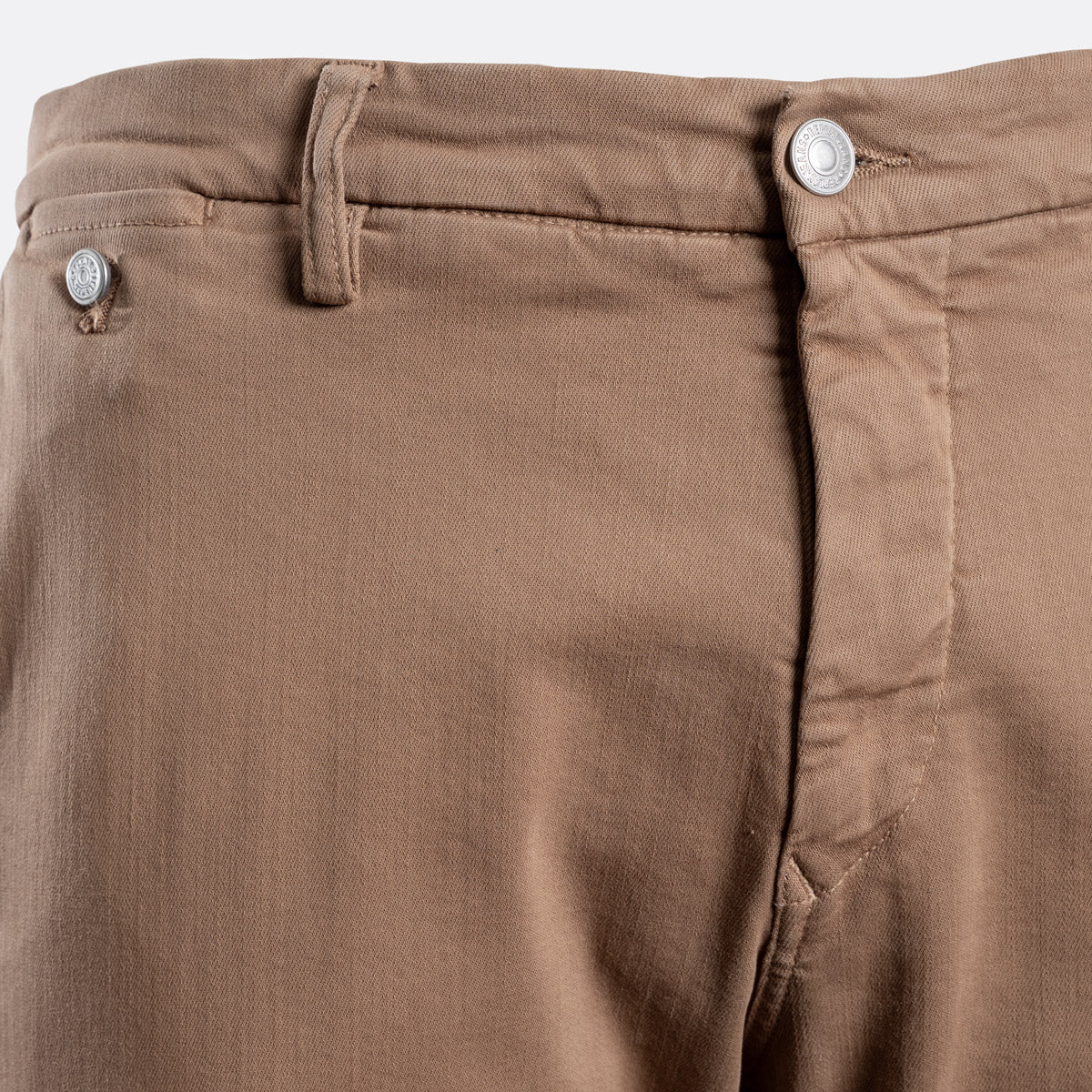 Close-up of the waistband of brown chino pants, showing the belt loops, button fly, and a side pocket with a silver button. Replay Chino available at Sakks Menswear in Southampton.