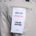 Close-up of beige Replay Hyperflex pants with a white paper hangtag reading 'REPLAY HYPERFLEX COLOR EDITION' attached near the back pocket. Replay Chinos available at Sakks Menswear in Southampton.