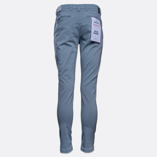 A pair of slim-fit blue jeans shown from the back, featuring a white paper tag attached to the back pocket, set against a plain light gray background. Replay Chinos available at Sakks Menswear in Southampton.