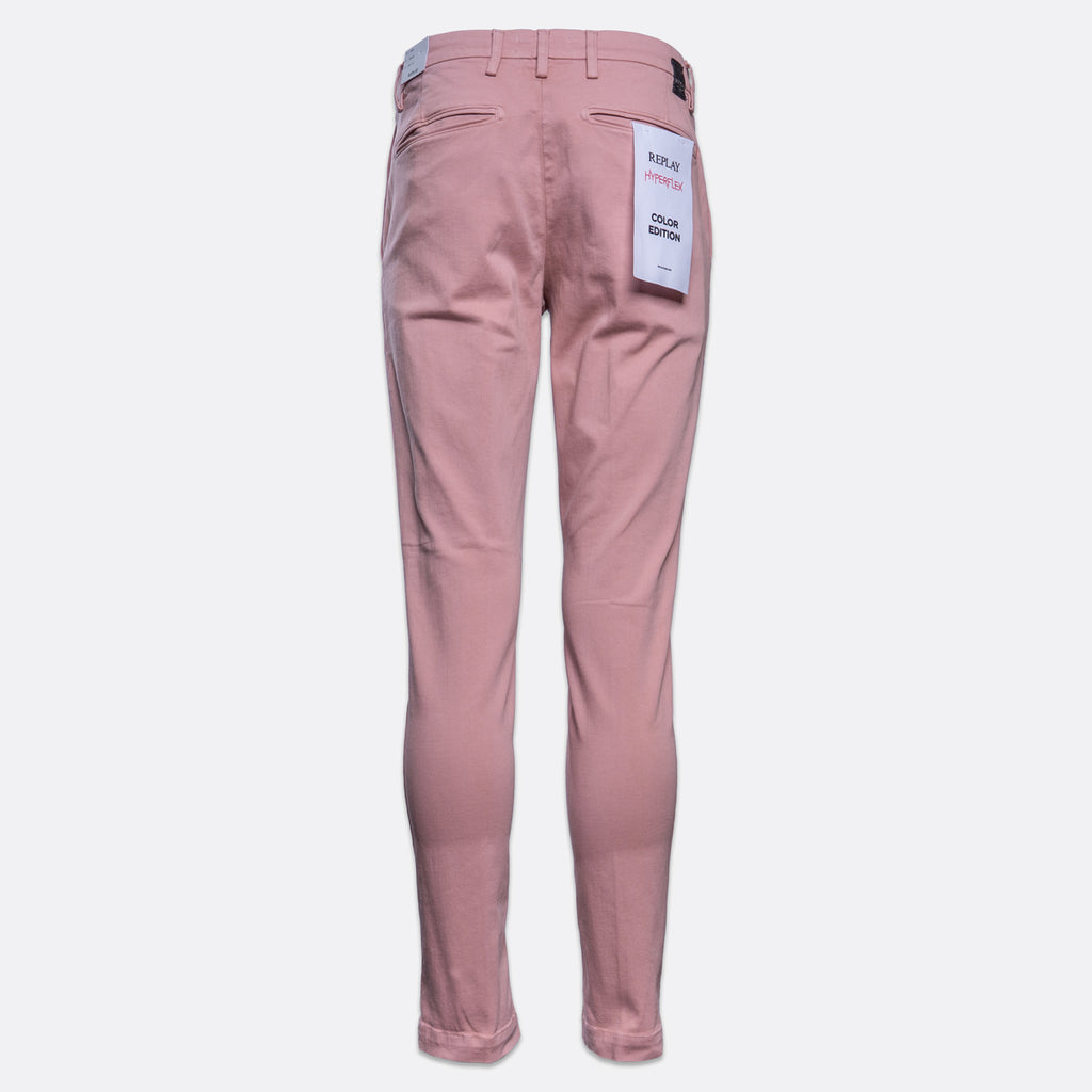 A pair of slim-fit, ankle-length trousers in a dusty rose pink color, shown from the back on a light gray background. A white paper tag is attached to the back pocket. Replay Chinos available at Sakks Menswear in Southampton.