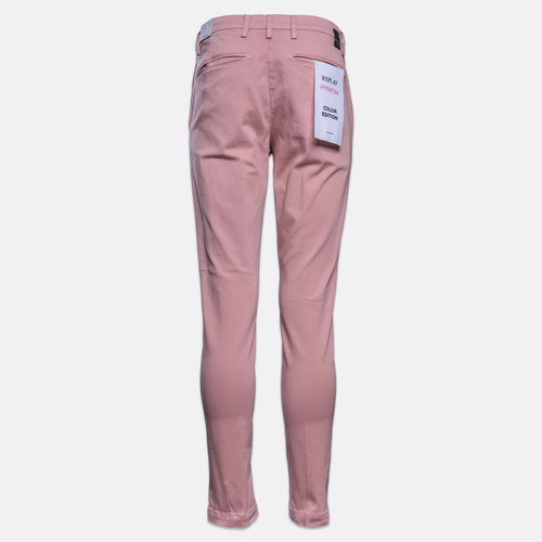 A pair of slim-fit, ankle-length trousers in a dusty rose pink color, shown from the back on a light gray background. A white paper tag is attached to the back pocket. Replay Chinos available at Sakks Menswear in Southampton.