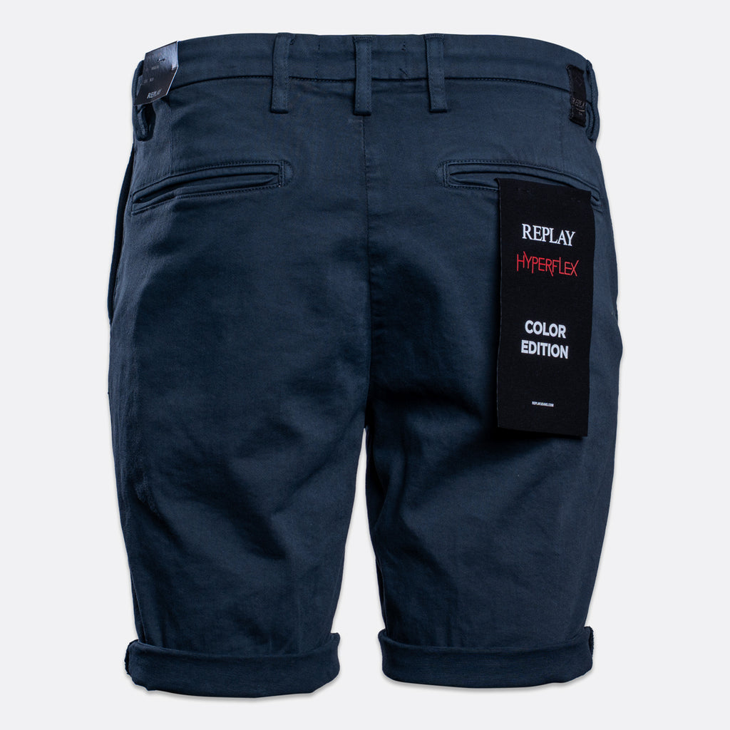 Dark navy blue denim shorts shown from the back, featuring a black paper tag on the right pocket that reads 'REPLAY HYPERFLEX COLOR EDITION'. Replay Shorts available at Sakks Menswear in Southampton.