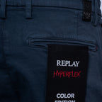 Close-up of dark navy blue Replay pants showing the back pocket and a black hangtag with white and red text reading 'REPLAY HYPERFLEX COLOR EDITION'. Replay Shorts available at Sakks Menswear in Southampton.