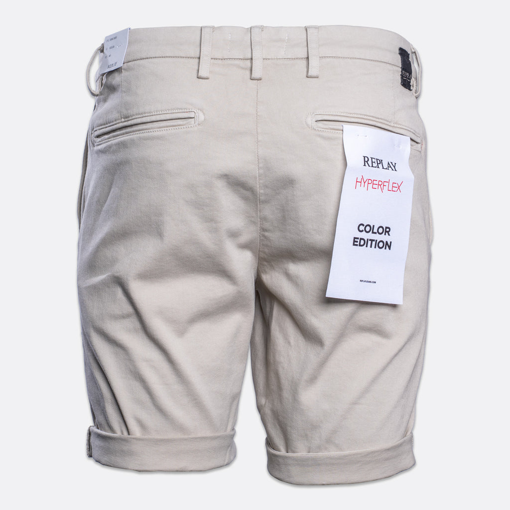 Back view of light beige chino shorts with rolled cuffs, featuring a white paper tag on the right pocket that reads 'REPLAY HYPERFLEX COLOR EDITION'. Replay Shorts available at Sakks Menswear in Southampton.