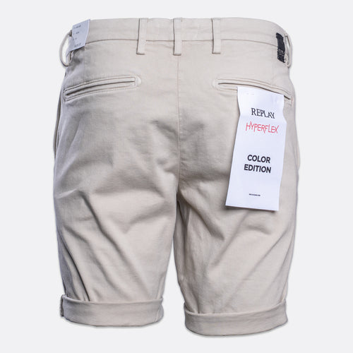 Back view of light beige chino shorts with rolled cuffs, featuring a white paper tag on the right pocket that reads 'REPLAY HYPERFLEX COLOR EDITION'. Replay Shorts available at Sakks Menswear in Southampton.