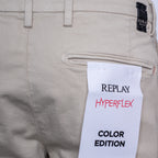 Close-up of khaki-colored Replay Hyperflex pants showing the back pocket and a white paper tag that reads 'REPLAY HYPERFLEX COLOR EDITION'. Replay Shorts available at Sakks Menswear in Southampton.