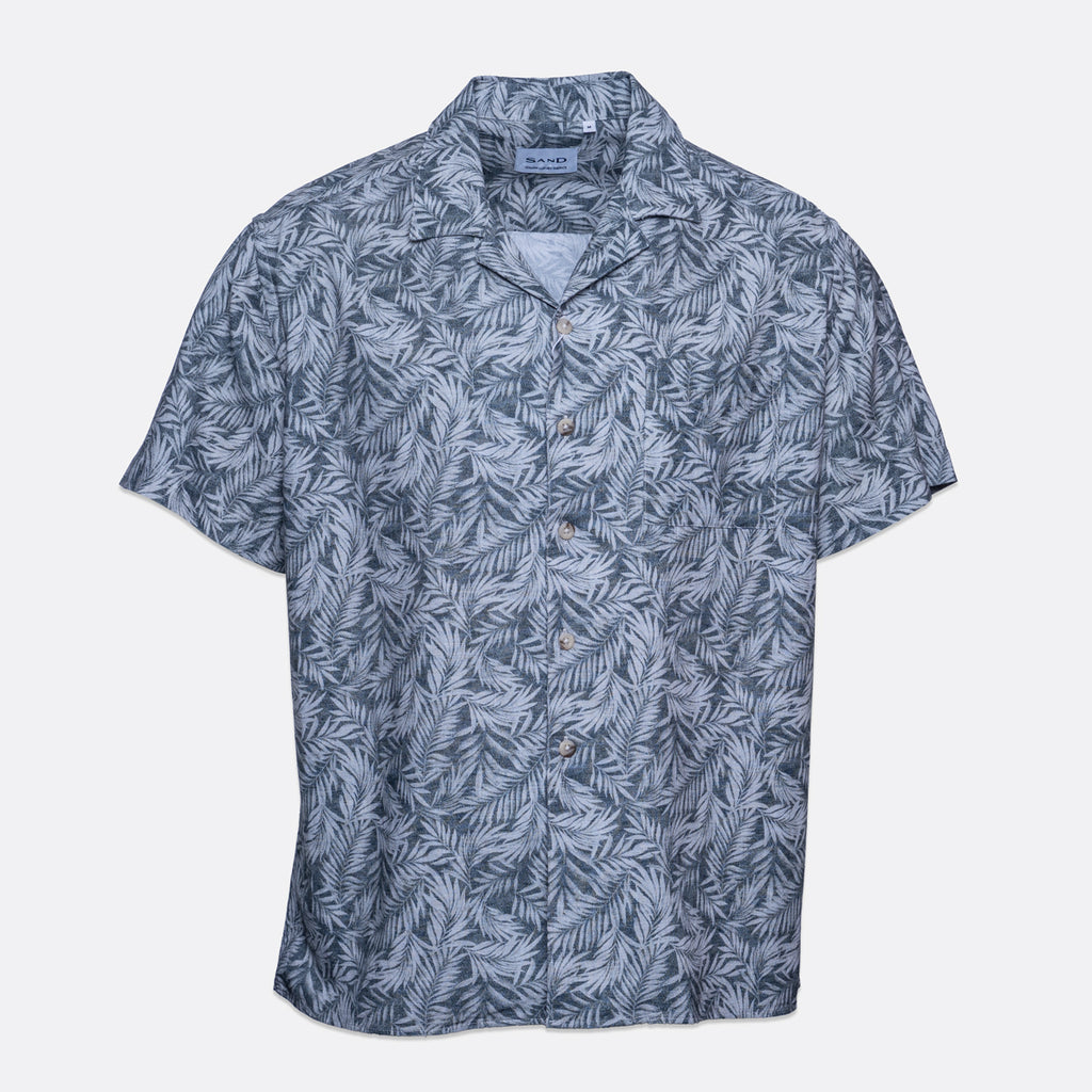 A short-sleeve button-up camp shirt with a blue and gray palm leaf pattern, displayed flat against a light gray background. Sand Copenhagen Short Sleeve Shirt available at Sakks Menswear in Southampton.
