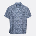 A short-sleeve button-up camp shirt with a blue and gray palm leaf pattern, displayed flat against a light gray background. Sand Copenhagen Short Sleeve Shirt available at Sakks Menswear in Southampton.