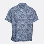 A short-sleeve button-up camp shirt with a blue and gray palm leaf pattern, displayed flat against a light gray background. Sand Copenhagen Short Sleeve Shirt available at Sakks Menswear in Southampton.