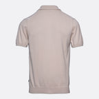A light beige short-sleeve polo shirt shown from the back, featuring subtle white stripe details on the shoulders, set against a plain light gray background. Sand Copenhagen Polo available at Sakks Menswear in Southampton.