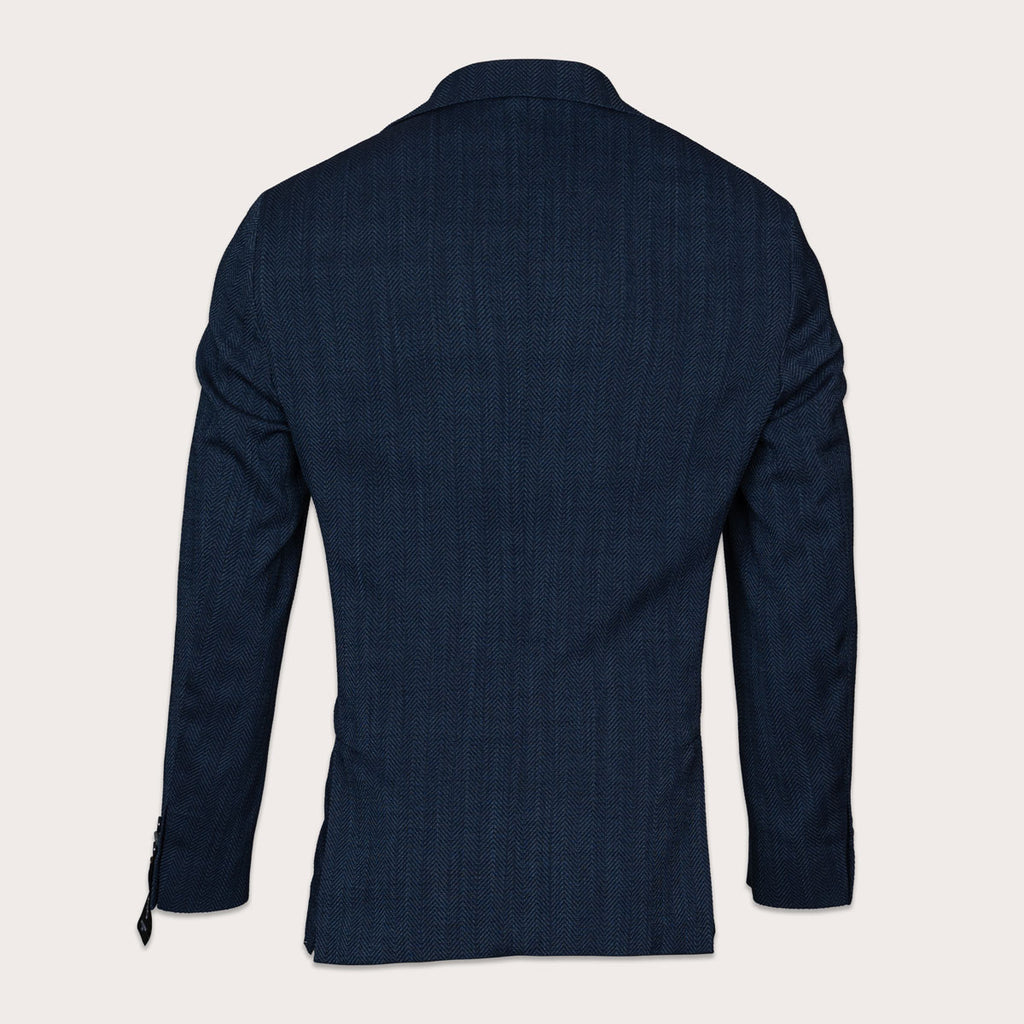 The back view of a men's dark navy blue textured blazer, displayed on a clean, solid off-white background. Sand Copenhagen Blazers available at Sakks Menswear in Southampton.