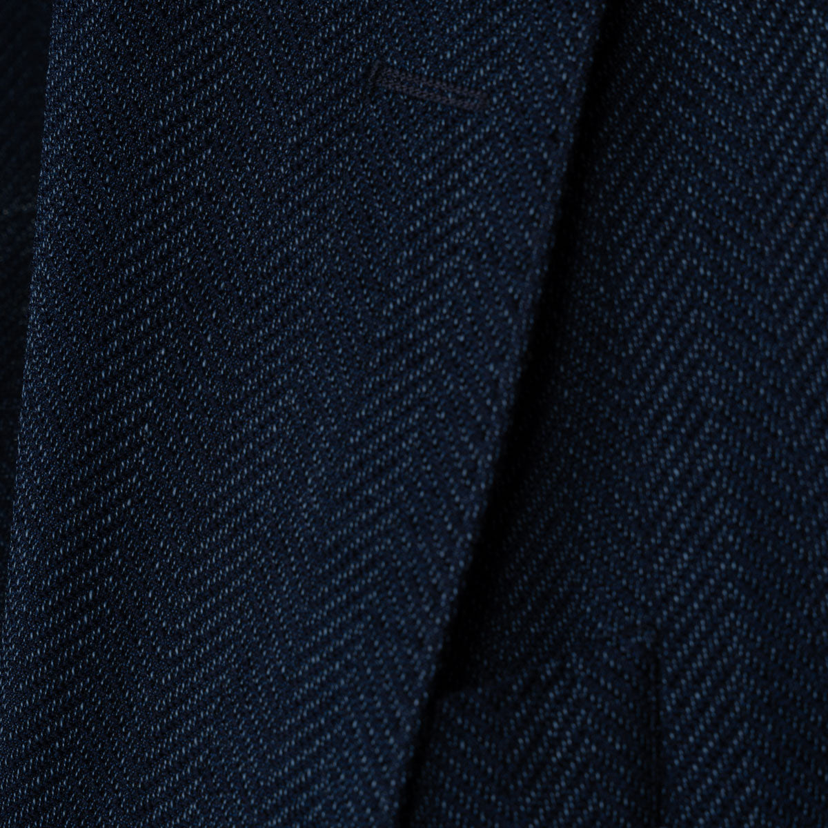 Close-up of a dark navy blue textured fabric with a fine woven herringbone pattern. Sand Copenhagen Blazers available at Sakks Menswear in Southampton.