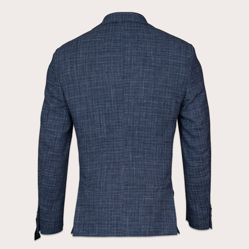 A men's navy blue textured blazer shown from the back, featuring a subtle woven grid pattern and a classic collar, set against a solid off-white background. Sand Copenhagen Blazers available at Sakks Menswear in Southampton.