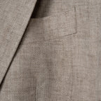 Close-up of a beige and brown herringbone tweed fabric with a pocket and lapel detail. Sand Copenhagen Blazer available at Sakks Menswear in Southampton.