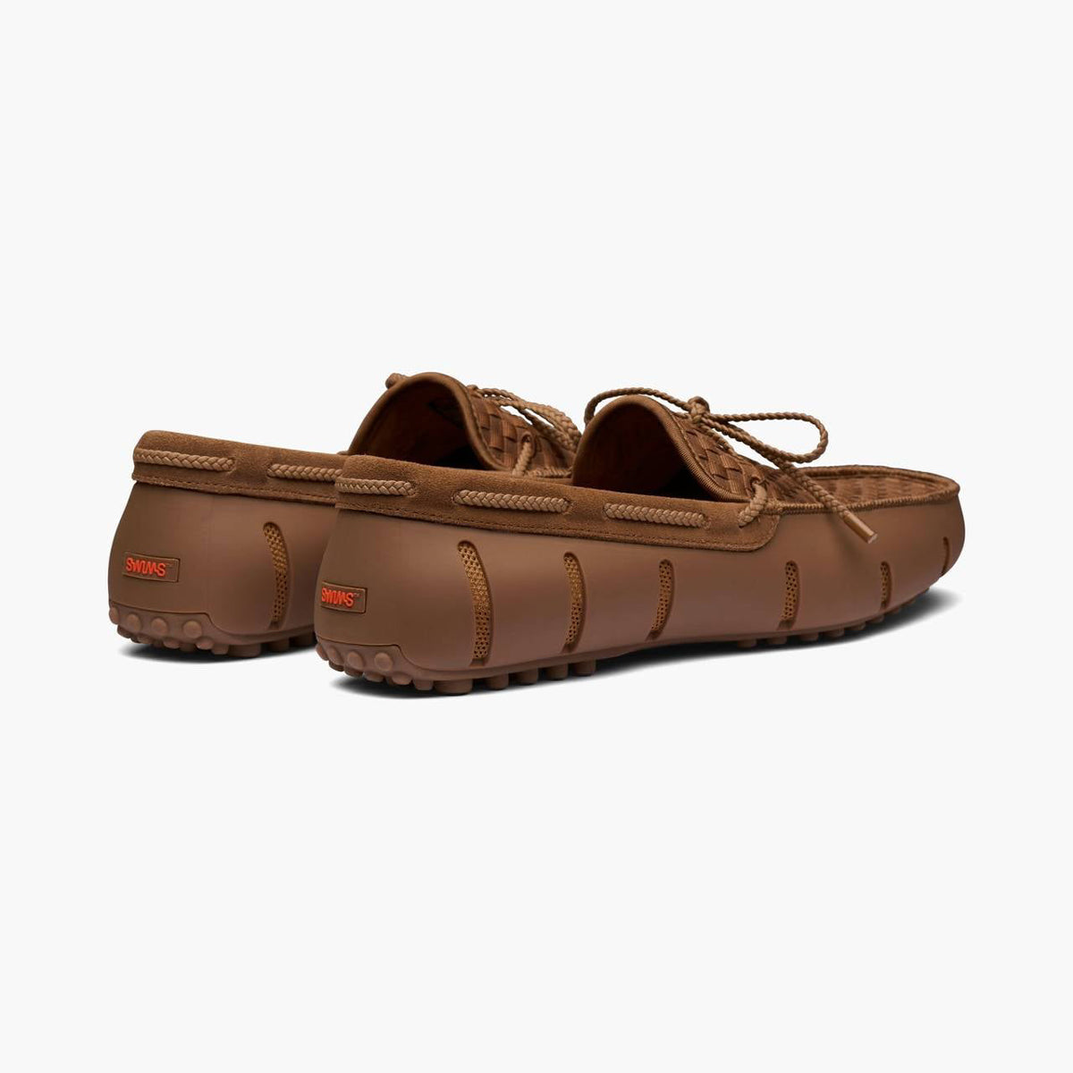 A pair of brown suede moccasin-style driving shoes with matching brown laces, shown from a three-quarters rear angle on a light gray background. SWIMS Loafers available at Sakks Menswear in Southampton.