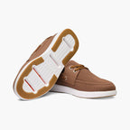 A pair of men's casual boat-style shoes in brown mesh and leather, shown on a clean white background. One shoe is positioned to display the textured brown outsole with a white midsole and a hint of red accent, while the other shows the side profile with brown laces and a white sole. SWIMS Boat Shoes available at Sakks Menswear in Southampton.