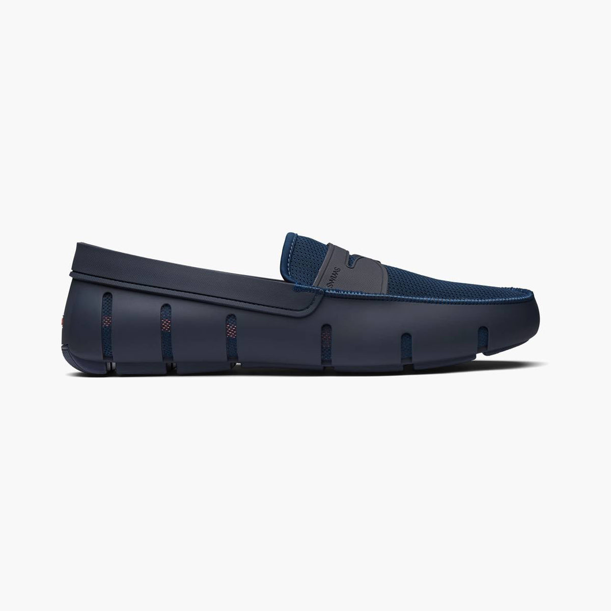 A single navy blue slip-on loafer with a textured knit upper and a molded sole, shown in a side profile on a light gray background. SWIMS Loafers available at Sakks Menswear in Southampton.