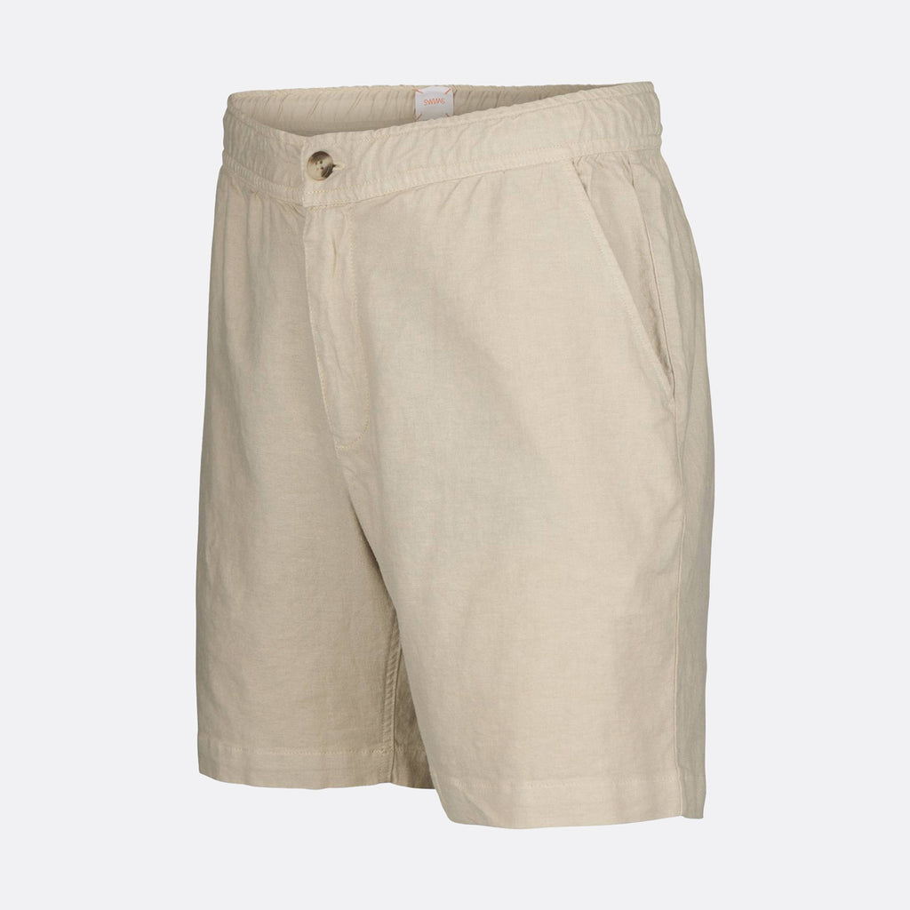 Beige linen shorts with a buttoned waistband and side pockets, shown on a light gray background. SWIMS Shorts available at Sakks Menswear in Southampton.