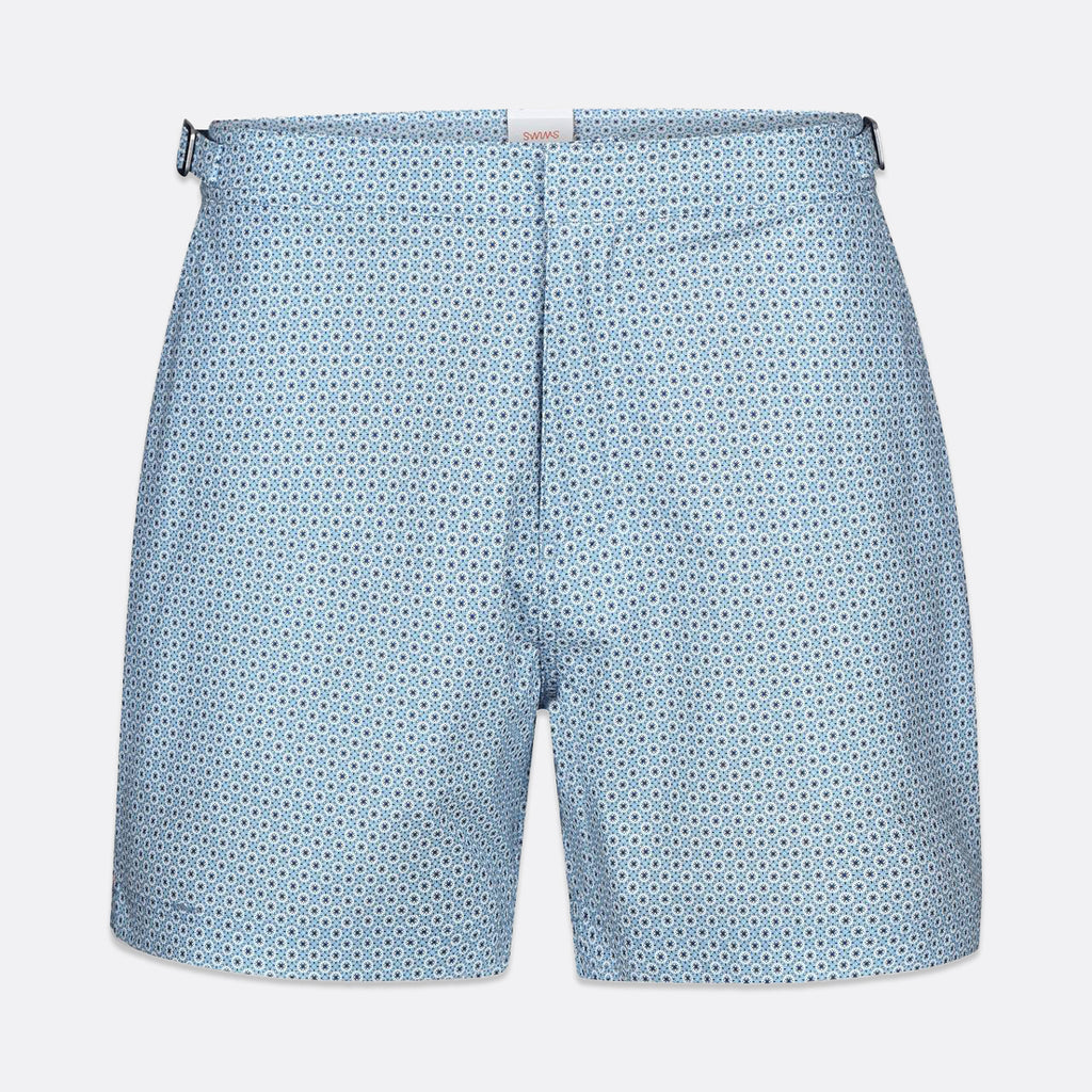 Light blue shorts with a small repeating dark blue geometric pattern, shown flat against a light gray background. SWIMS Swim Shorts available at Sakks Menswear in Southampton.