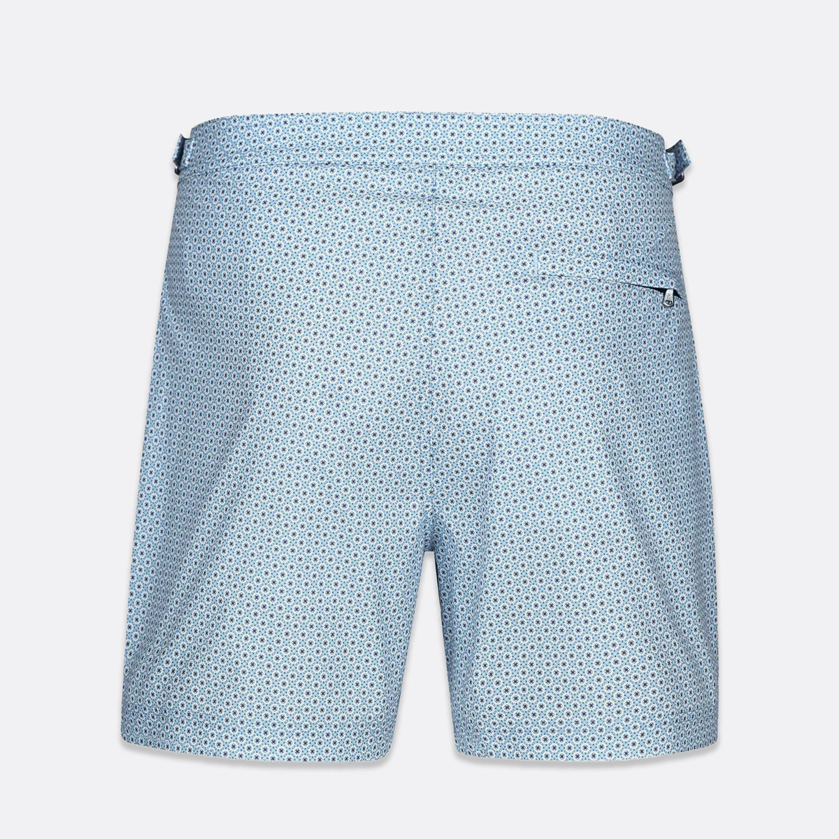 Light blue swim trunks with a small dark blue geometric pattern, featuring a side pocket and a waistband with side tabs, shown against a light gray background. SWIMS Swim Shorts available at Sakks Menswear in Southampton.