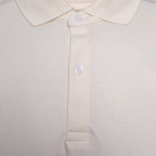 Close-up of a polo shirt collar and button placket in a light cream or off-white color, showing the fabric texture and white buttons. Thomas Maine Polo available at Sakks Menswear in Southampton.
