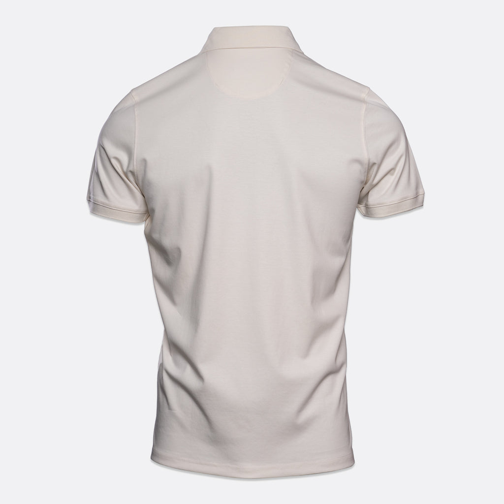 The back view of a short-sleeve polo shirt in a light cream or off-white color, displayed on a clean, light gray background. Thomas Maine Polo available at Sakks Menswear in Southampton.