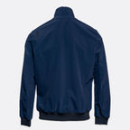 A navy blue lightweight jacket shown from the back, featuring a stand-up collar, ribbed cuffs, and a ribbed hem, photographed against a light gray background. UBR Jacket available at Sakks Menswear in Southampton.