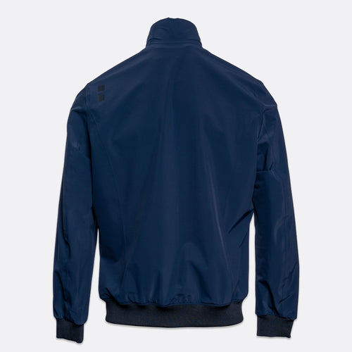 A navy blue lightweight jacket shown from the back, featuring a stand-up collar, ribbed cuffs, and a ribbed hem, photographed against a light gray background. UBR Jacket available at Sakks Menswear in Southampton.