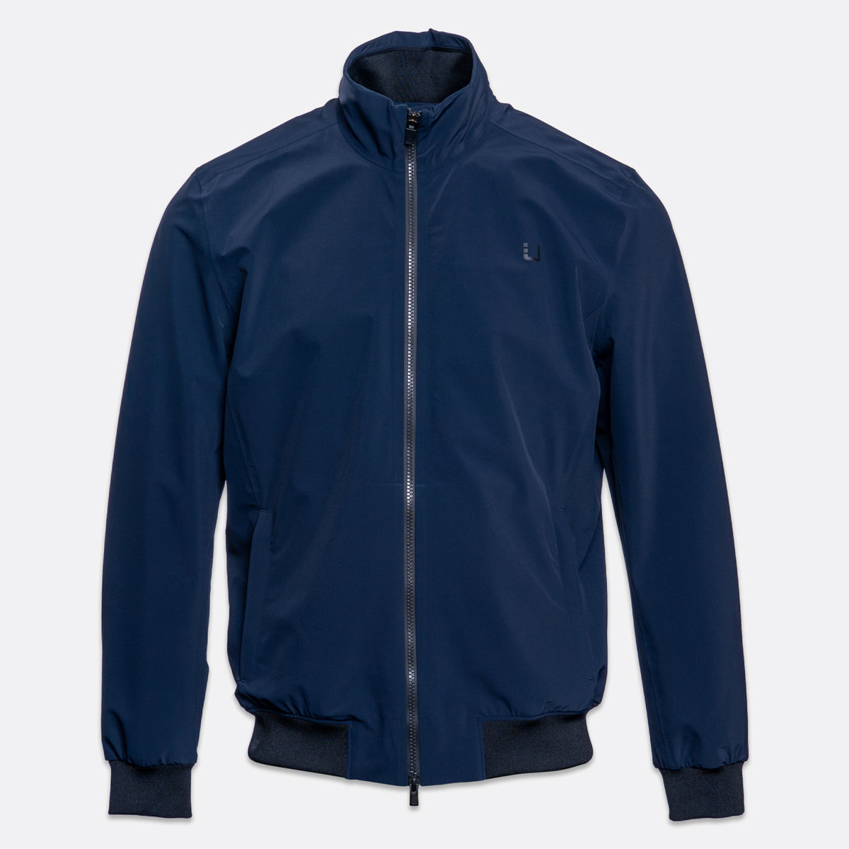 A navy blue lightweight zip-up jacket with a stand-up collar, ribbed cuffs, and a ribbed hem, shown against a light gray background. UBR Jacket available at Sakks Menswear in Southampton.