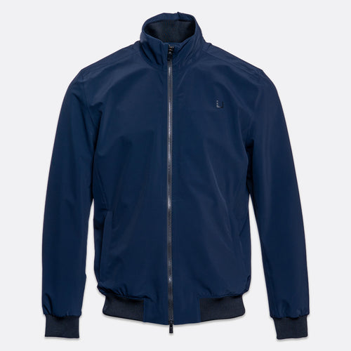 A navy blue lightweight zip-up jacket with a stand-up collar, ribbed cuffs, and a ribbed hem, shown against a light gray background. UBR Jacket available at Sakks Menswear in Southampton.