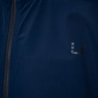 Close-up of a dark navy blue jacket with a black zipper on the left and a small dark gray stylized 'U' logo on the chest. UBR Jacket available at Sakks Menswear in Southampton.