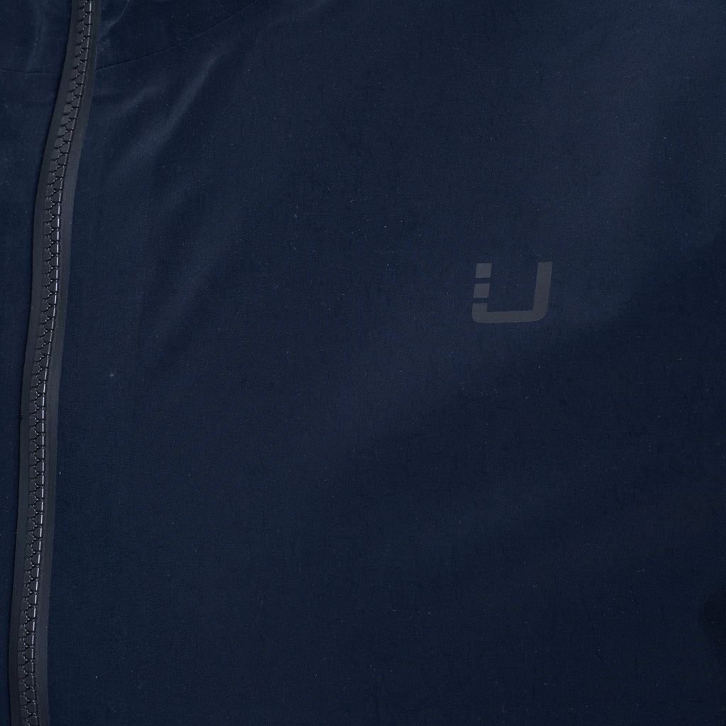 Close-up of a dark navy blue jacket with a dark gray logo on the chest and a black zipper running down the left side. UBR Jacket available at Sakks Menswear in Southampton.