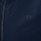 Close-up of a dark navy blue jacket with a dark gray logo on the chest and a black zipper running down the left side. UBR Jacket available at Sakks Menswear in Southampton.