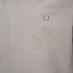 Close-up of a light gray or off-white fabric surface with a small gray stylized 'U' logo near the upper right area. UBR Jacket available at Sakks Menswear in Southampton.