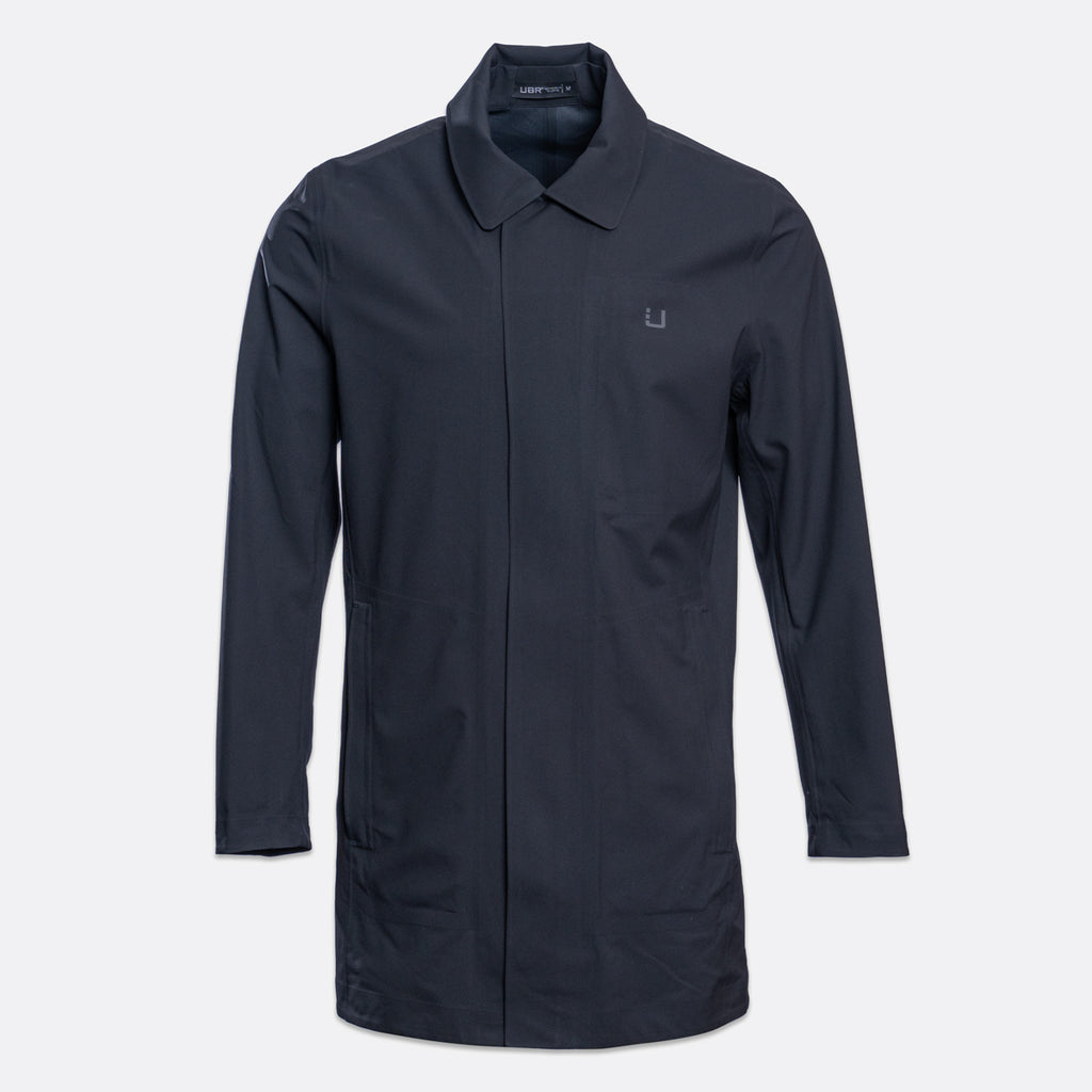 A dark navy blue utility jacket with a pointed collar, front zipper, and a small embroidered logo on the left chest, displayed on a light gray background. UBR Jacket available at Sakks Menswear in Southampton.