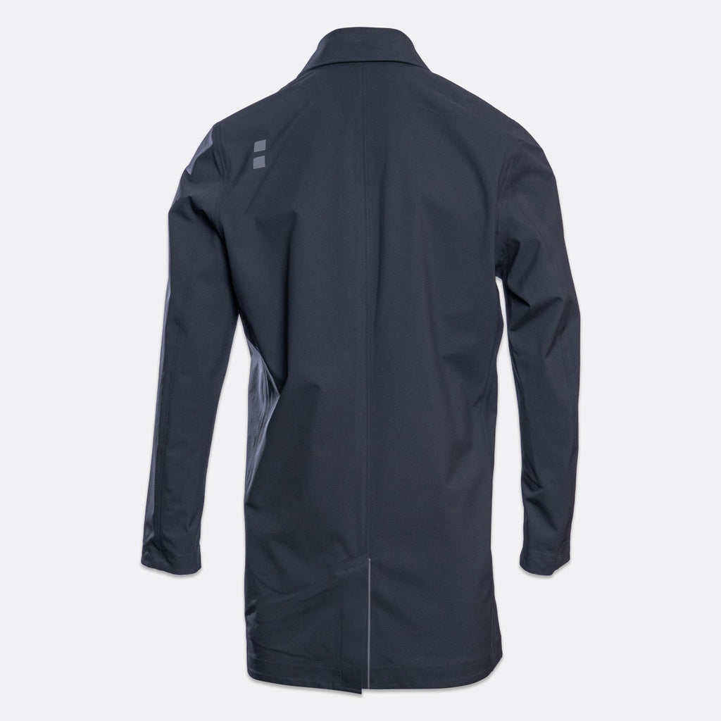 A dark navy blue long-sleeve jacket shown from the back, featuring a subtle gray geometric logo on the upper left shoulder, set against a light gray background. UBR Jacket available at Sakks Menswear in Southampton.