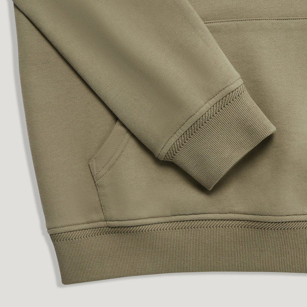 Close-up of a ribbed-knit sweatshirt sleeve cuff and hem in a muted olive-khaki color, showing the texture and stitching details. Belstaff Hoodie. Sakks Menswear Southampton.