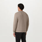 A man stood facing away in a beige coloured Belstaff Sweatshirt. The model is stood in front of a grey background. Belstaff Sweatshirt. Sakks Menswear Southampton.