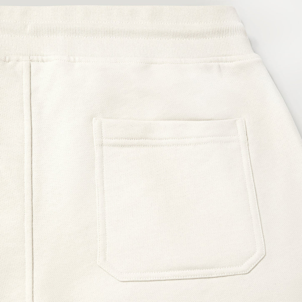 Close-up of a white or off-white fabric garment showing a rectangular front patch pocket and a ribbed waistband. Belstaff Sweatshorts. Sakks Menswear Southampton.