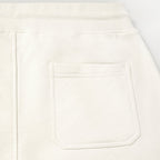 Close-up of a white or off-white fabric garment showing a rectangular front patch pocket and a ribbed waistband. Belstaff Sweatshorts. Sakks Menswear Southampton.